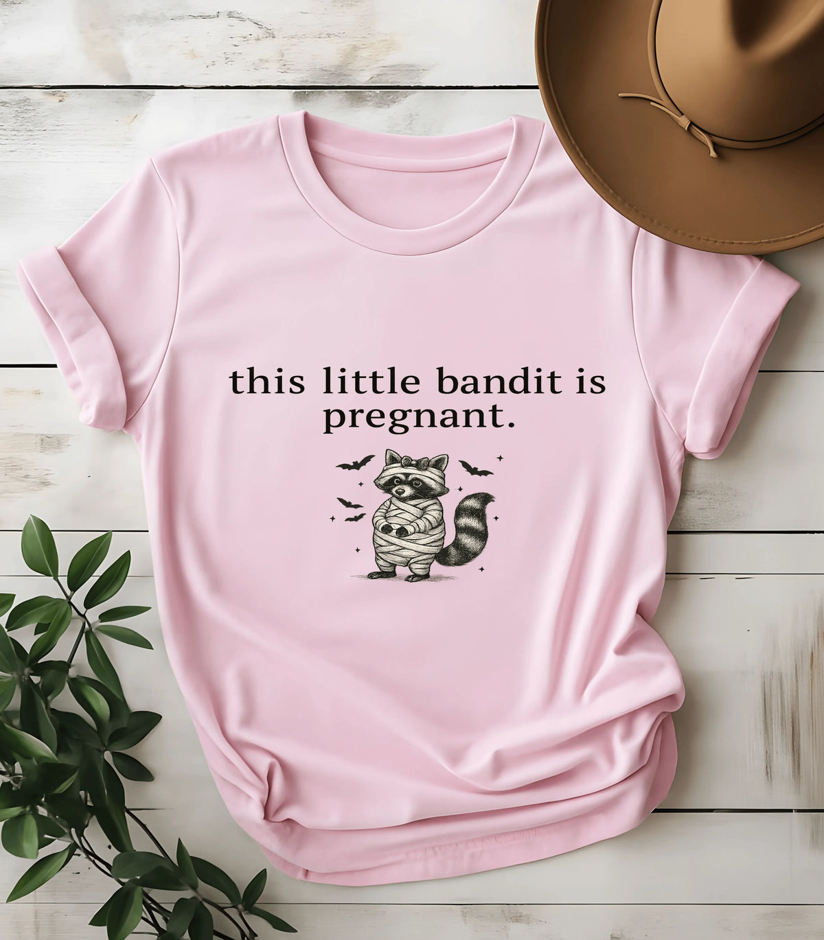 Funny raccoon graphic tee with 'this little bandit is pregnant' text on pink shirt