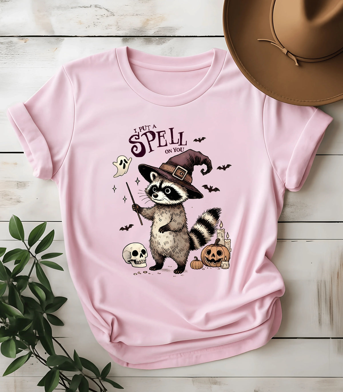 Funny raccoon witch graphic tee with Halloween design on pink shirt