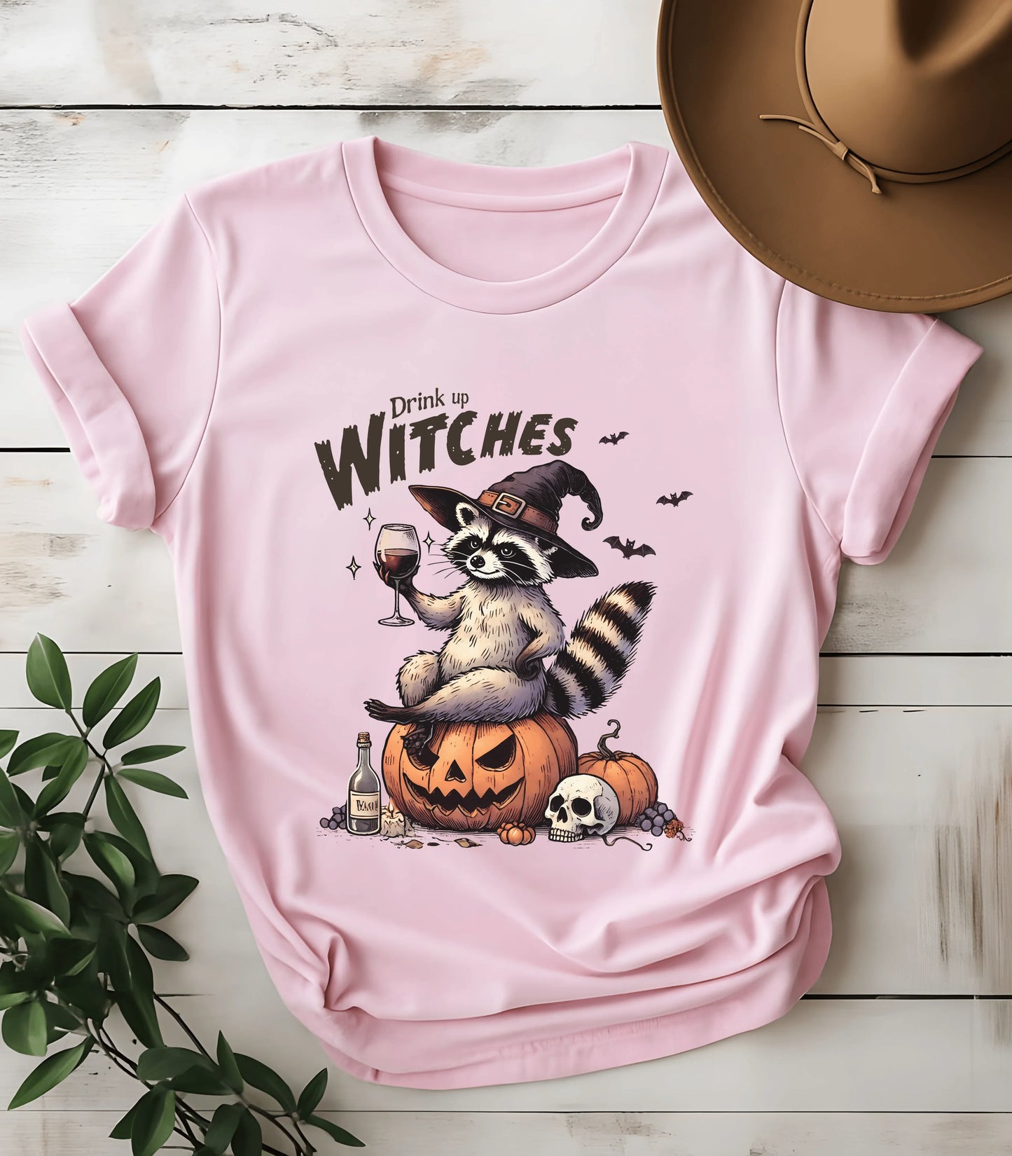 Funny raccoon witch graphic tee with 'Drink up Witches' on pink shirt