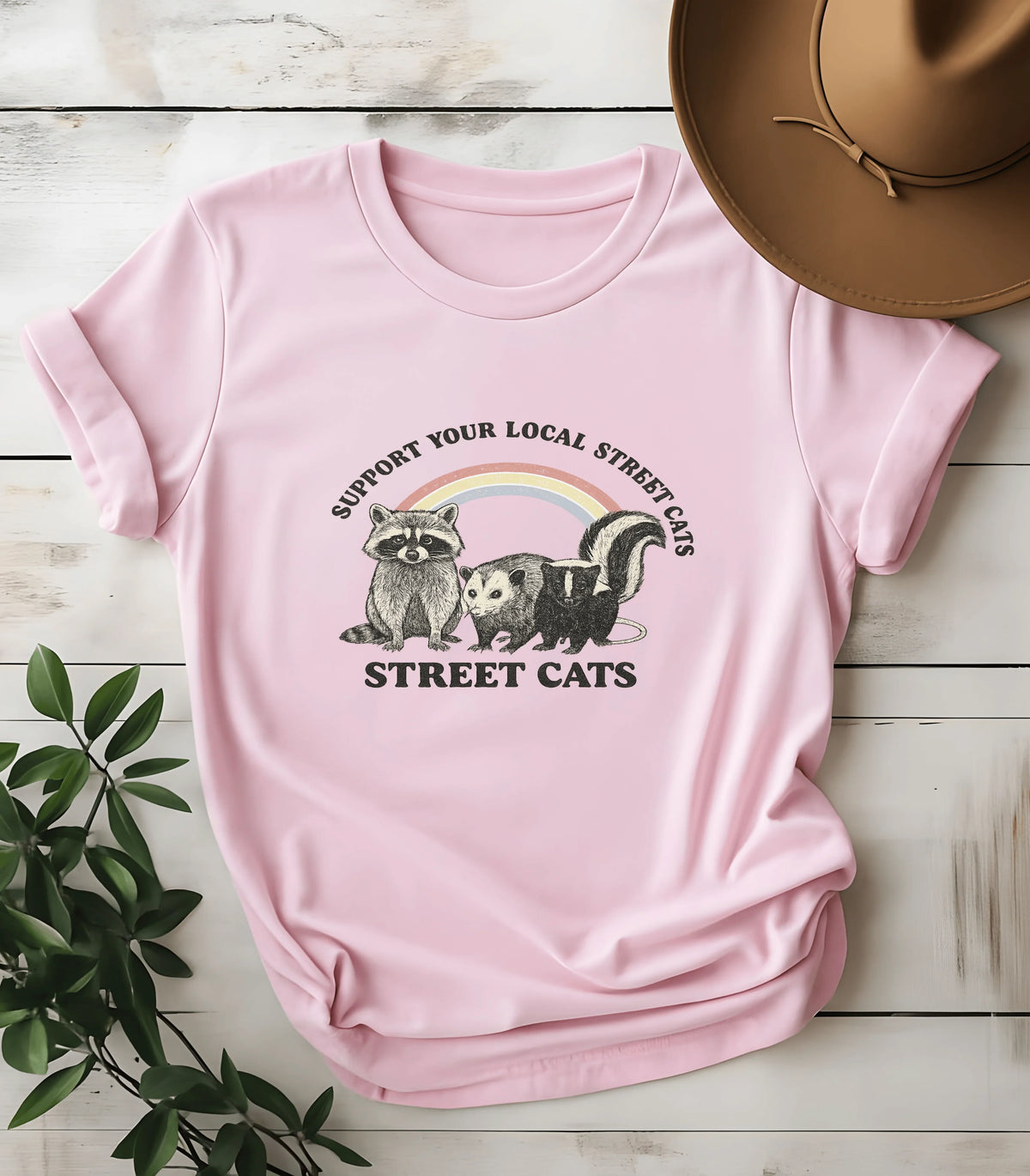 Pink graphic tee with raccoon, opossum, skunk and 'Street Cats' text under rainbow