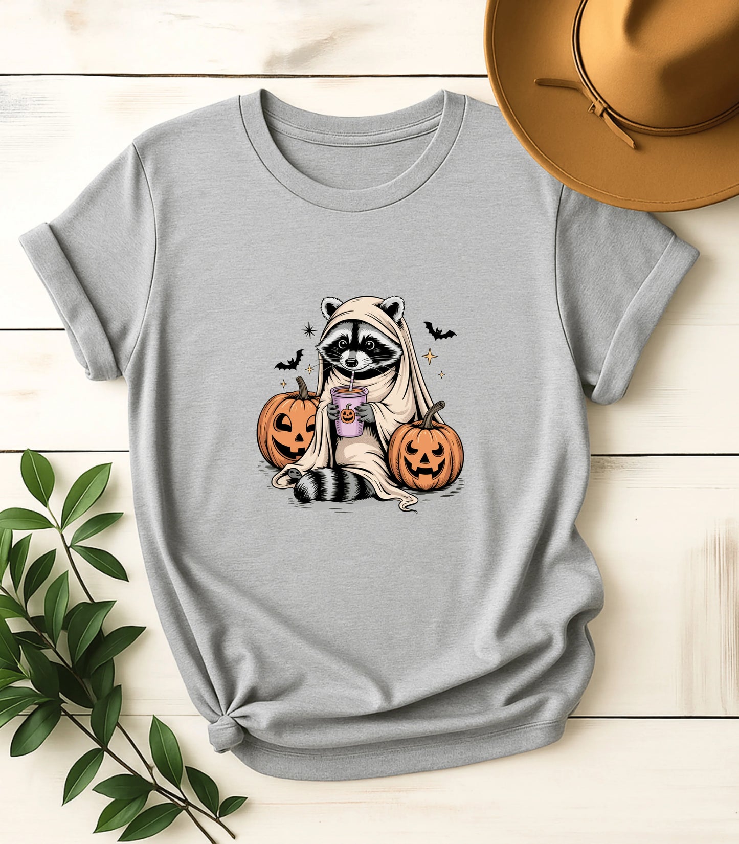 Funny raccoon in ghost costume with pumpkins and drink on gray tee