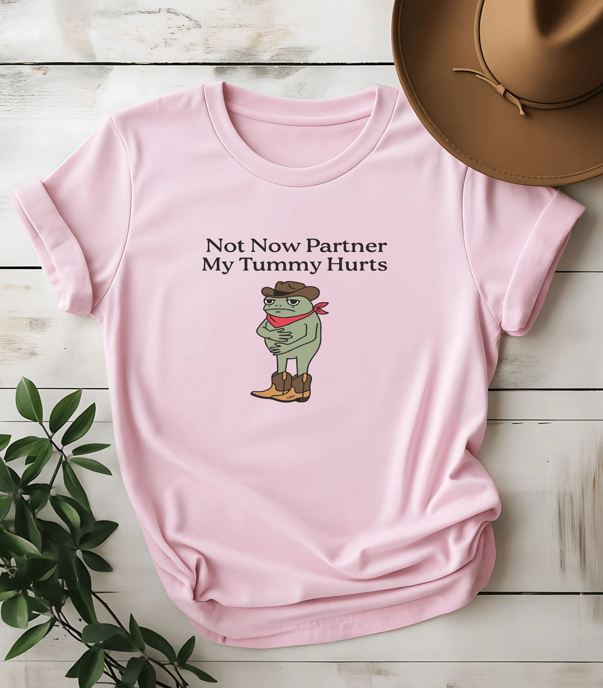 Pink graphic tee with frog cowboy saying Not Now Partner My Tummy Hurts