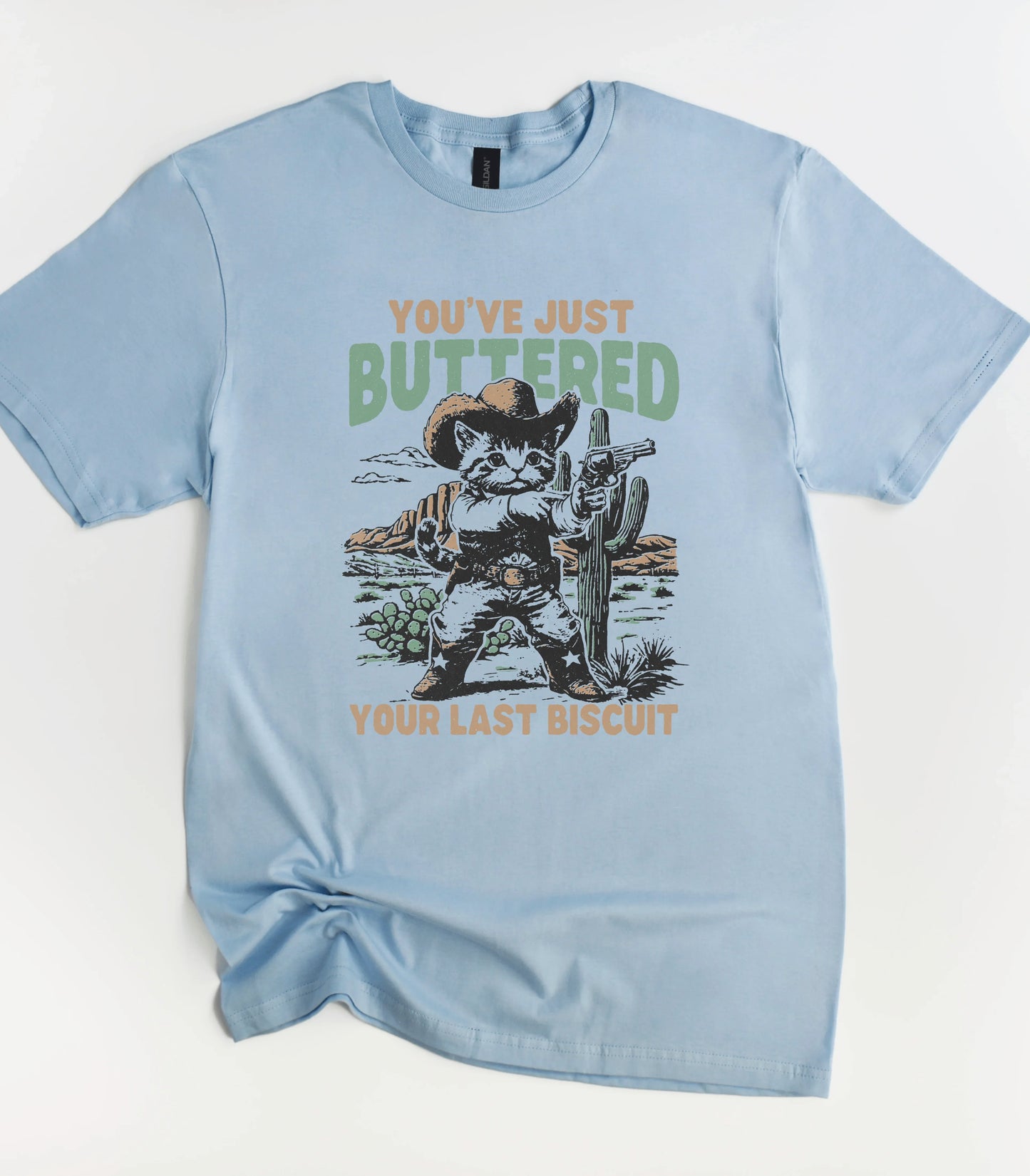 Funny cat graphic tee with cowboy cat holding gun and text 'You've Just Buttered Your Last Biscuit'