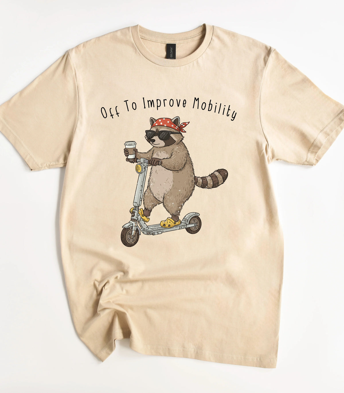 Funny raccoon on scooter graphic t-shirt with 'Off To Improve Mobility' text