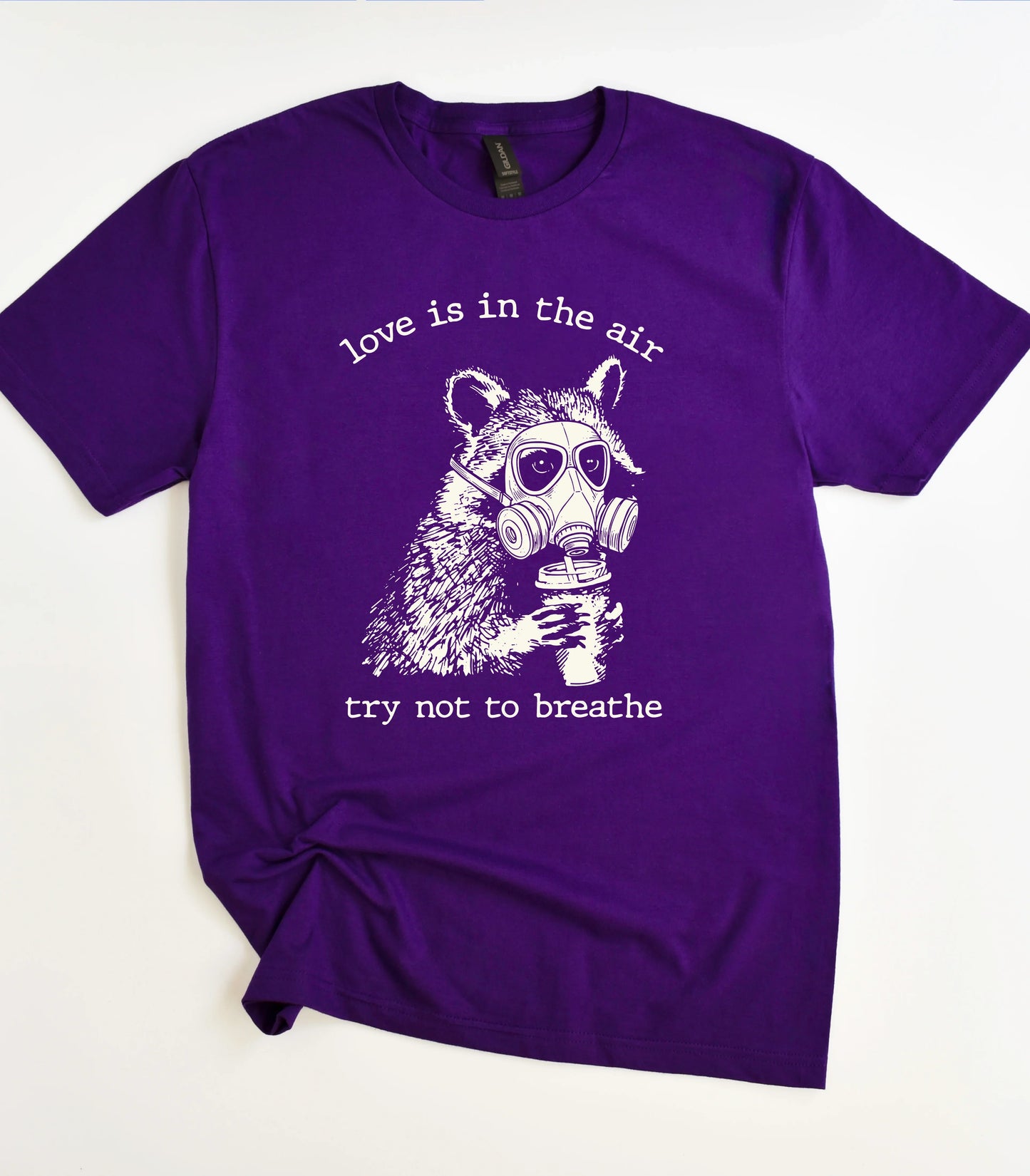 Funny raccoon graphic tee with gas mask and text 'love is in the air, try not to breathe'