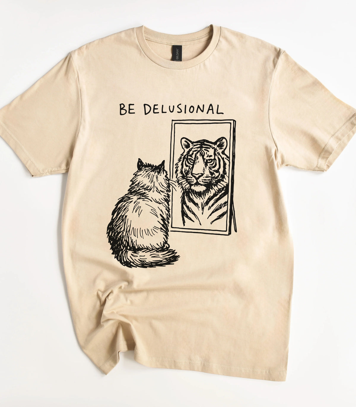 Funny cat graphic tee with 'BE DELUSIONAL' text and tiger mirror design